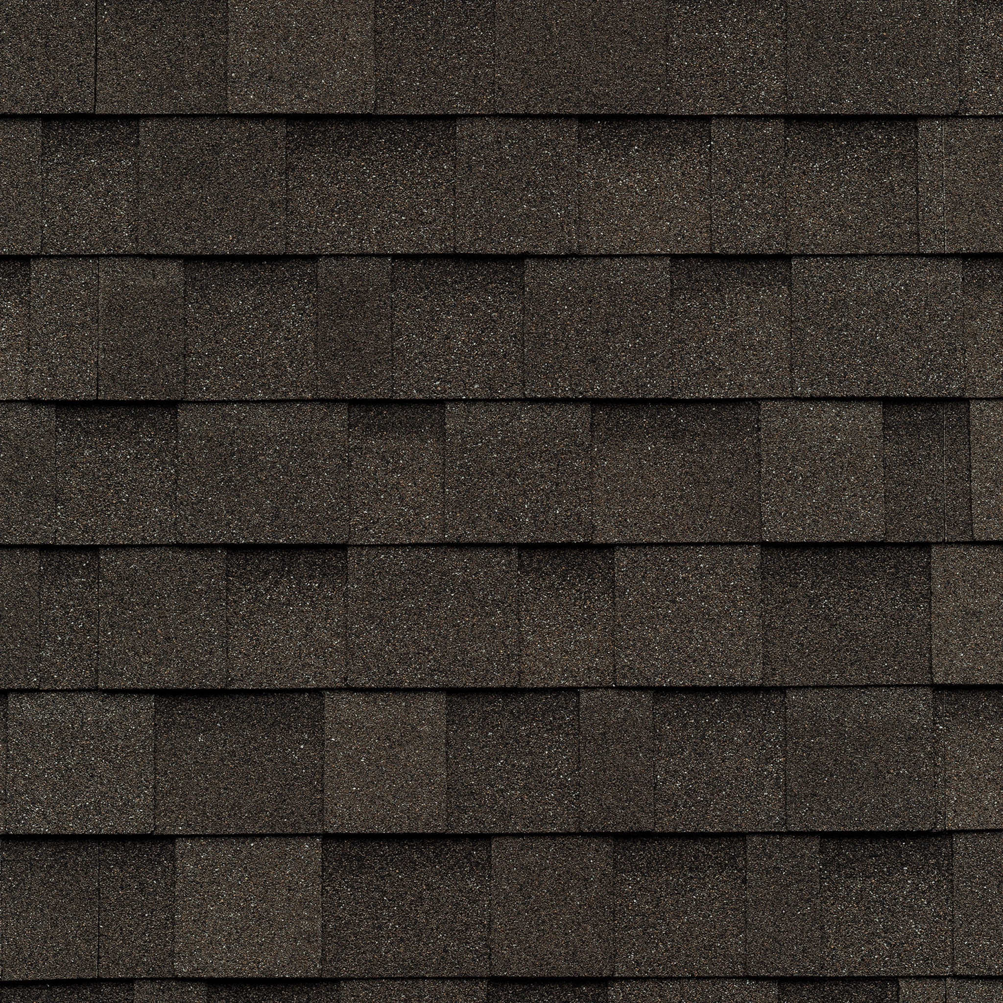 Close-up of overlapping dark gray asphalt roof shingles, reminiscent of the natural hues found in driftwood, arranged in a uniform pattern.