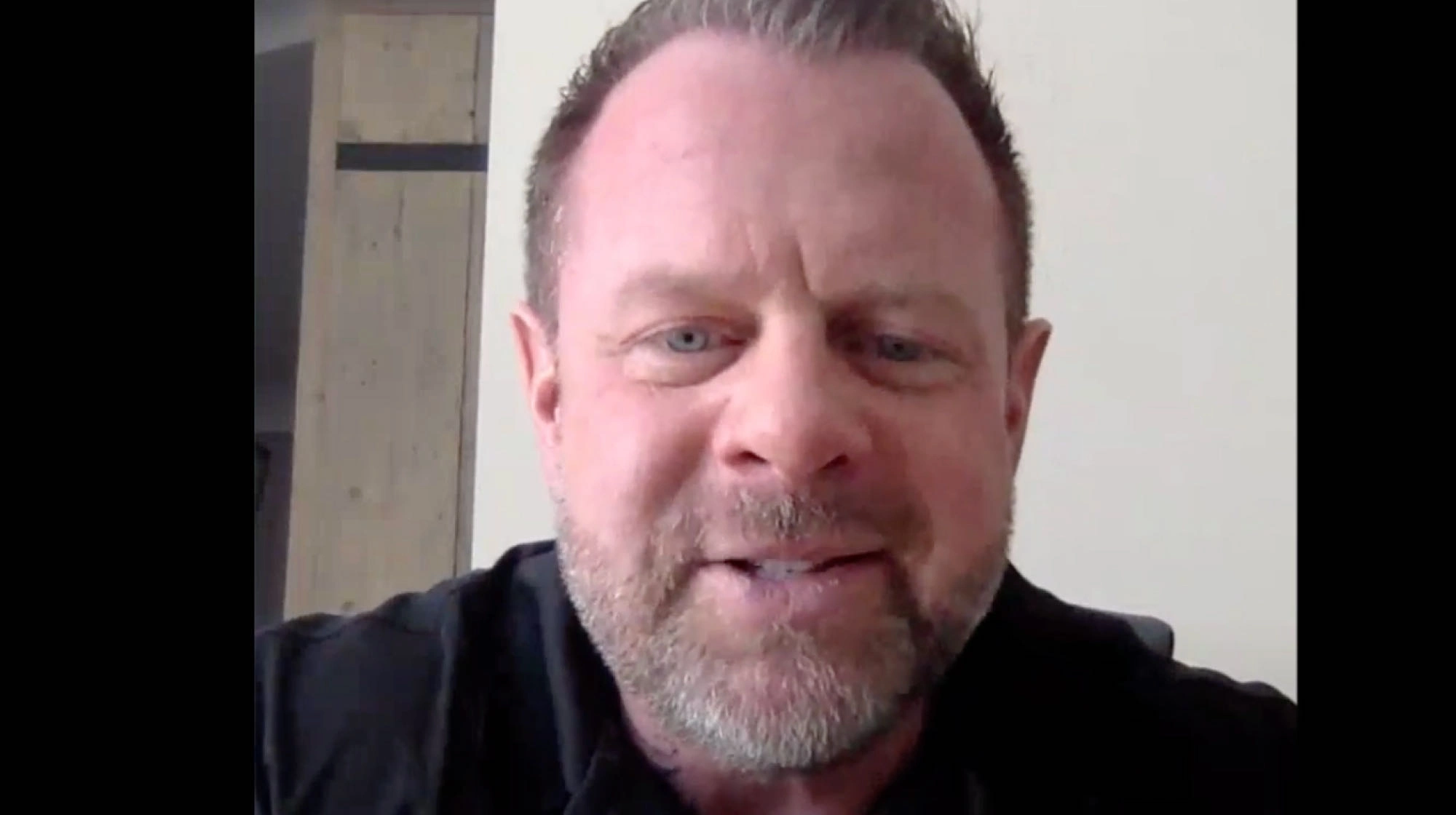 A person with short hair and a beard, smiling slightly, looks into the camera in a room with a light wall and wooden door. The benefits of choosing ROOFPRO for your projects are as clear as the warm atmosphere in this inviting space.